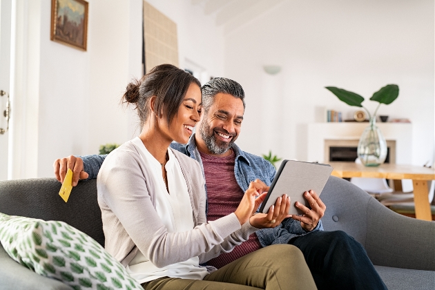 couple sat on sofa shopping online