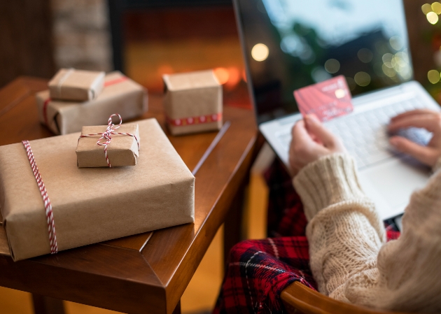 person shopping on line with gifts on a table in brown paper