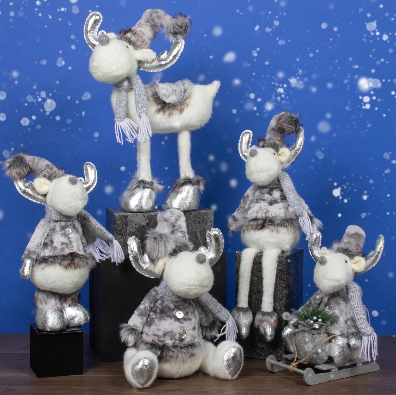 white fluffy reindeer in hats and scarves on a display with snowy backdrop