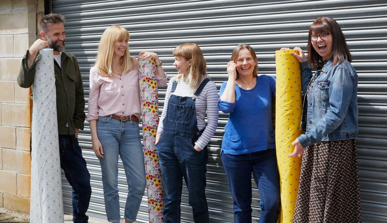 five people standing outside holding reems of beeswax paper in different patterns