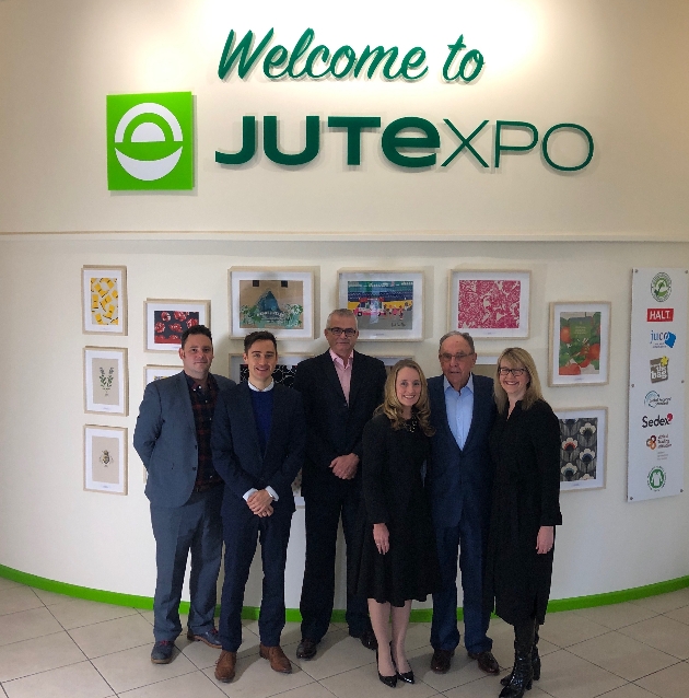 Jutexpo team in office in front of logo