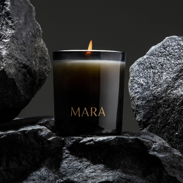 black candle lit among rocks