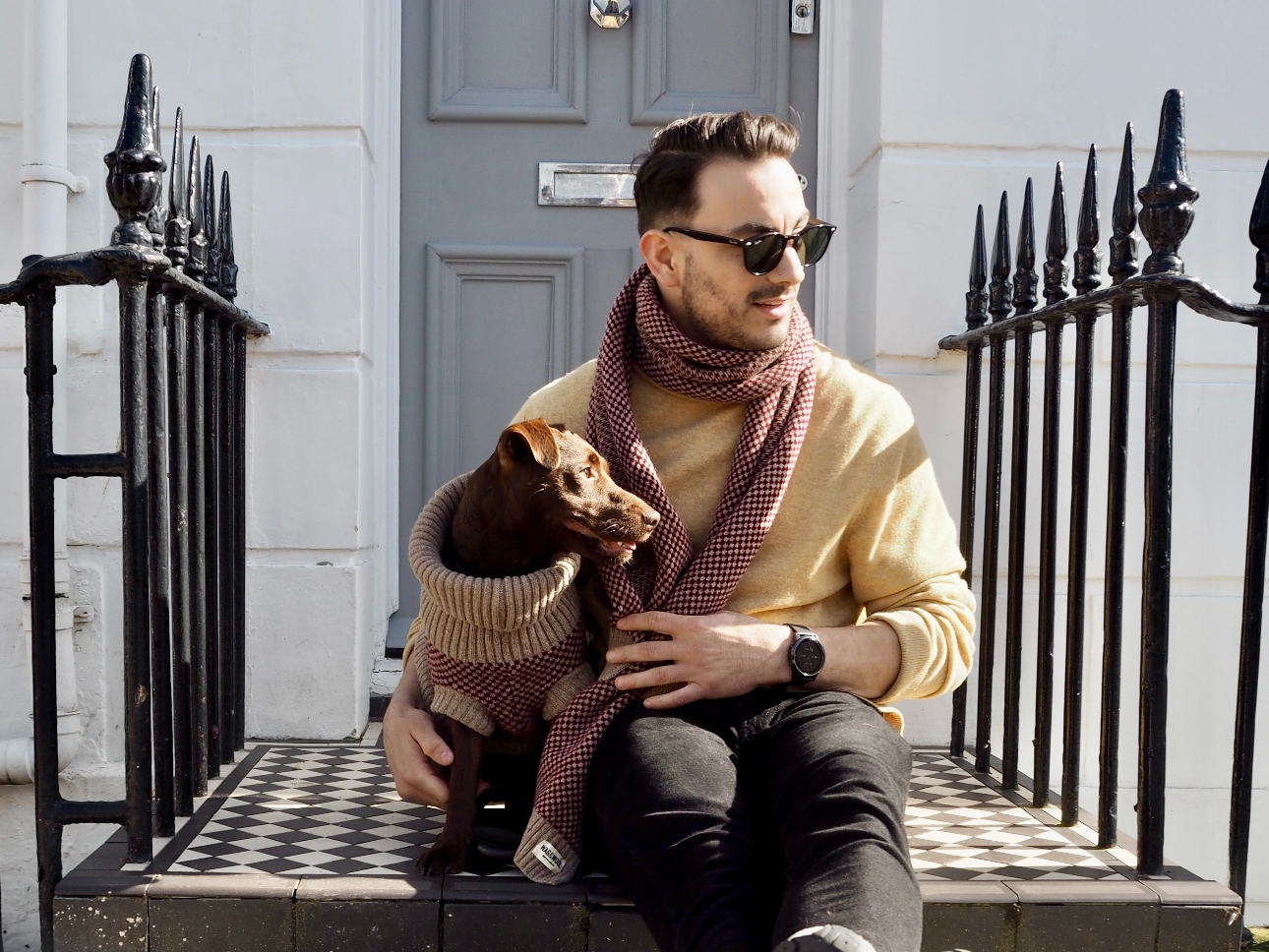 man on steps with dog both in matching scarves