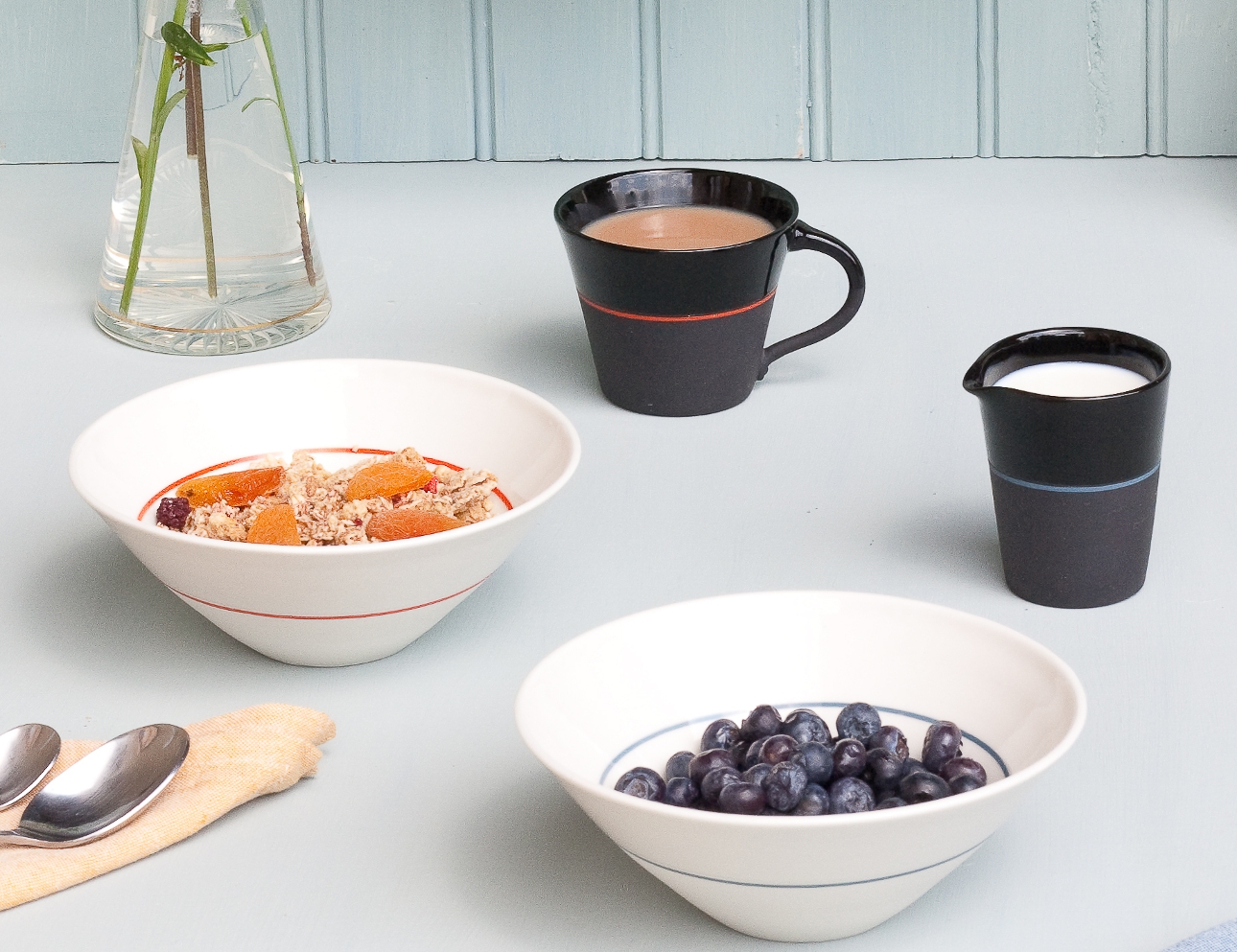 two white bowls with coloured lines and two black mugs with coloured lines