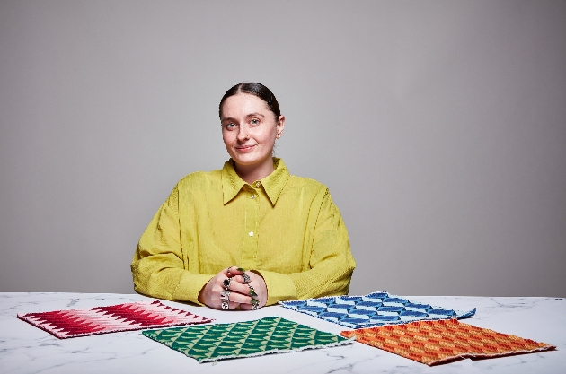 woman in yellow shirt at table with different colour swatches of material in front of her 