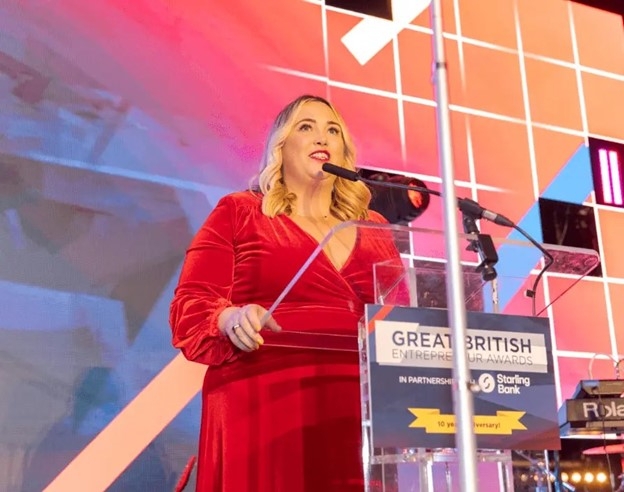 woman in red dress at podium on stage with microphone