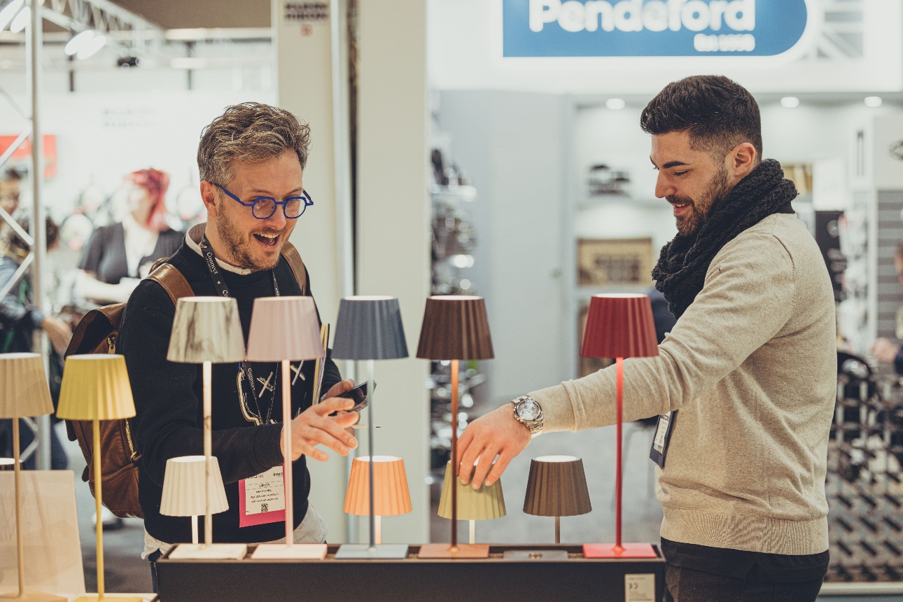 two men looking at table lamps at a trade show