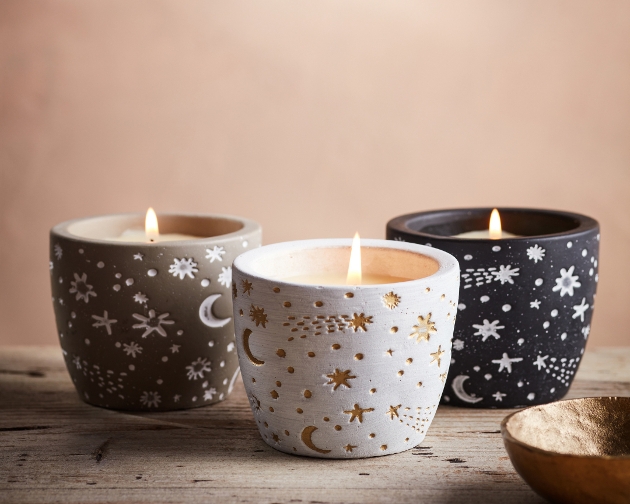 small candles in three pots, white black and stone with star print on