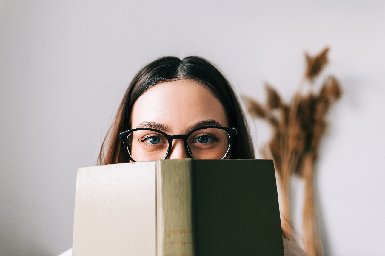 woman in glasses looking over a book