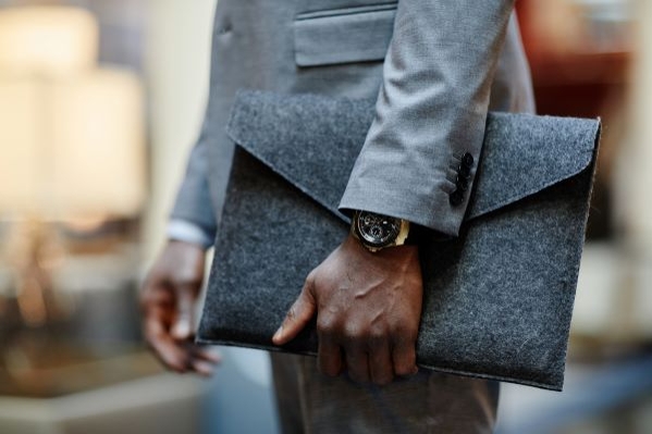 man wearing watch carrying laptop case