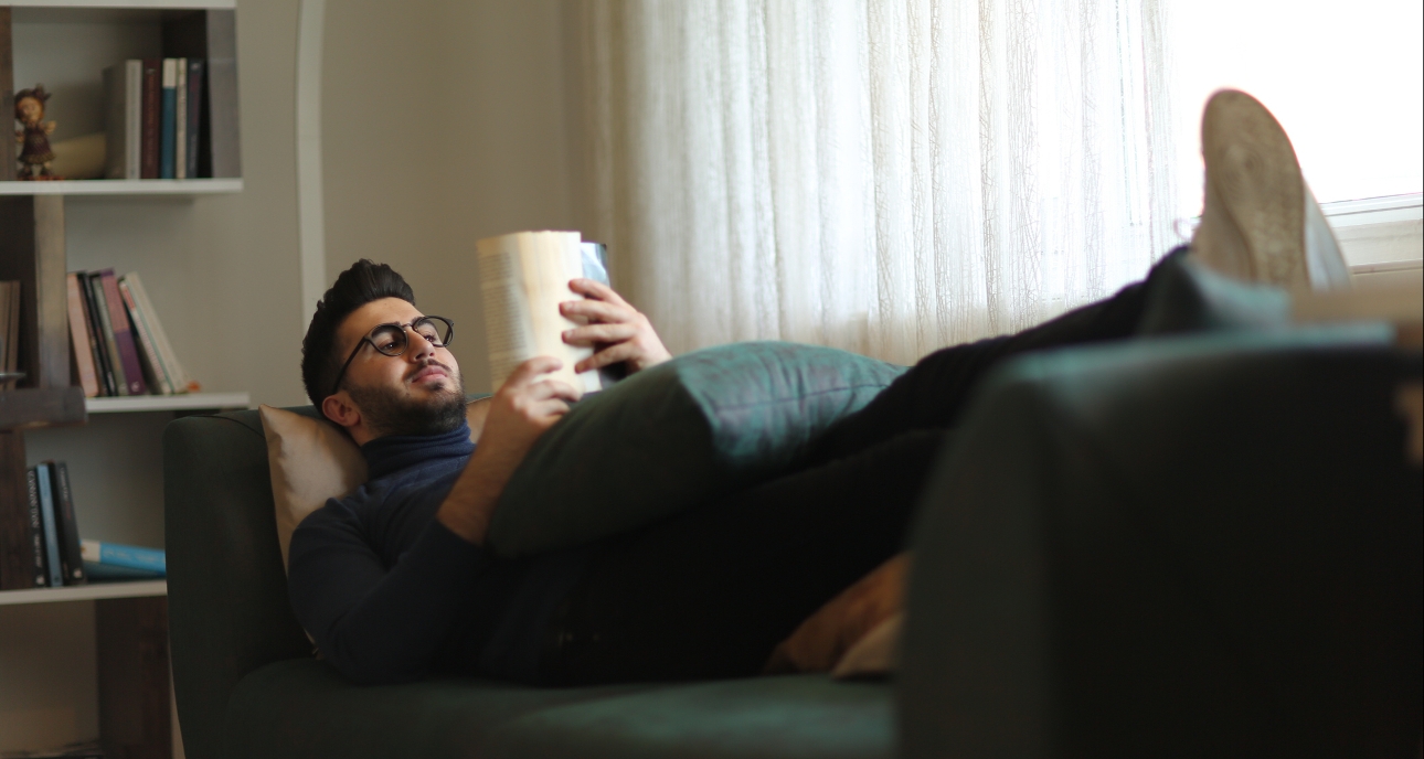 man laying on sofa reading a book