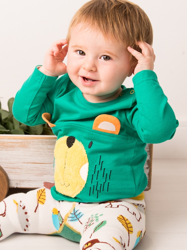 baby in green top with bear on it and printed leggins