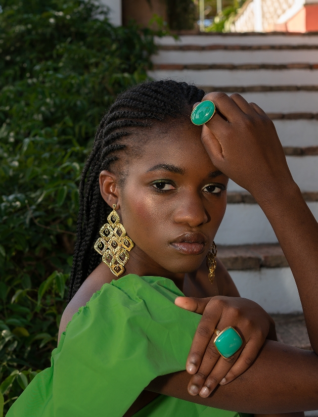 model in green top with large gold earrings and green rings on