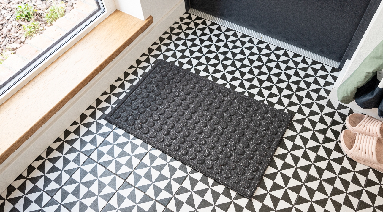 black door mat with raised circles on black and white floor