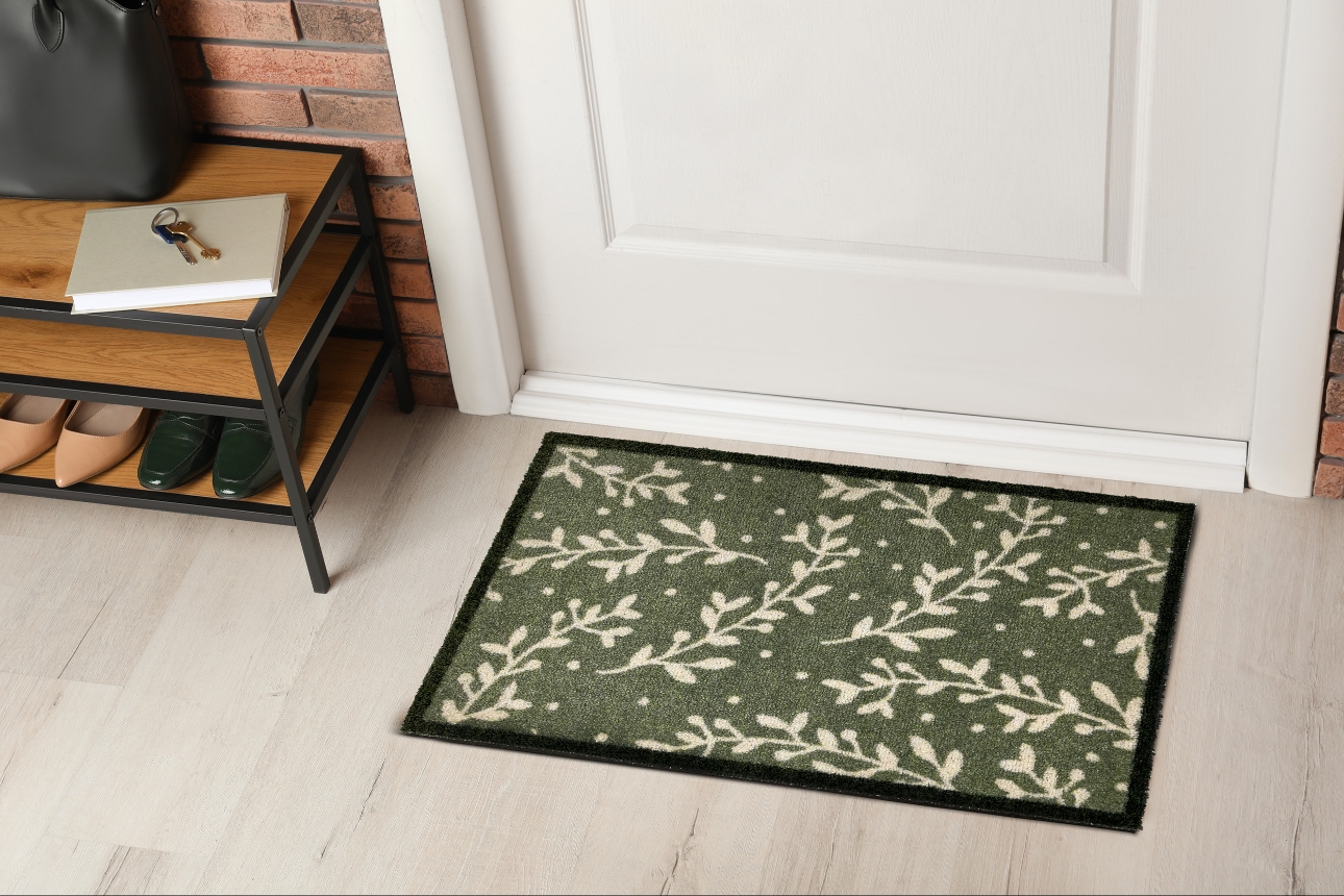 green door mat with white leaf design and black edge