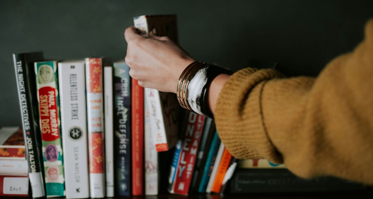 woman's hand placing a book on a bookshelf